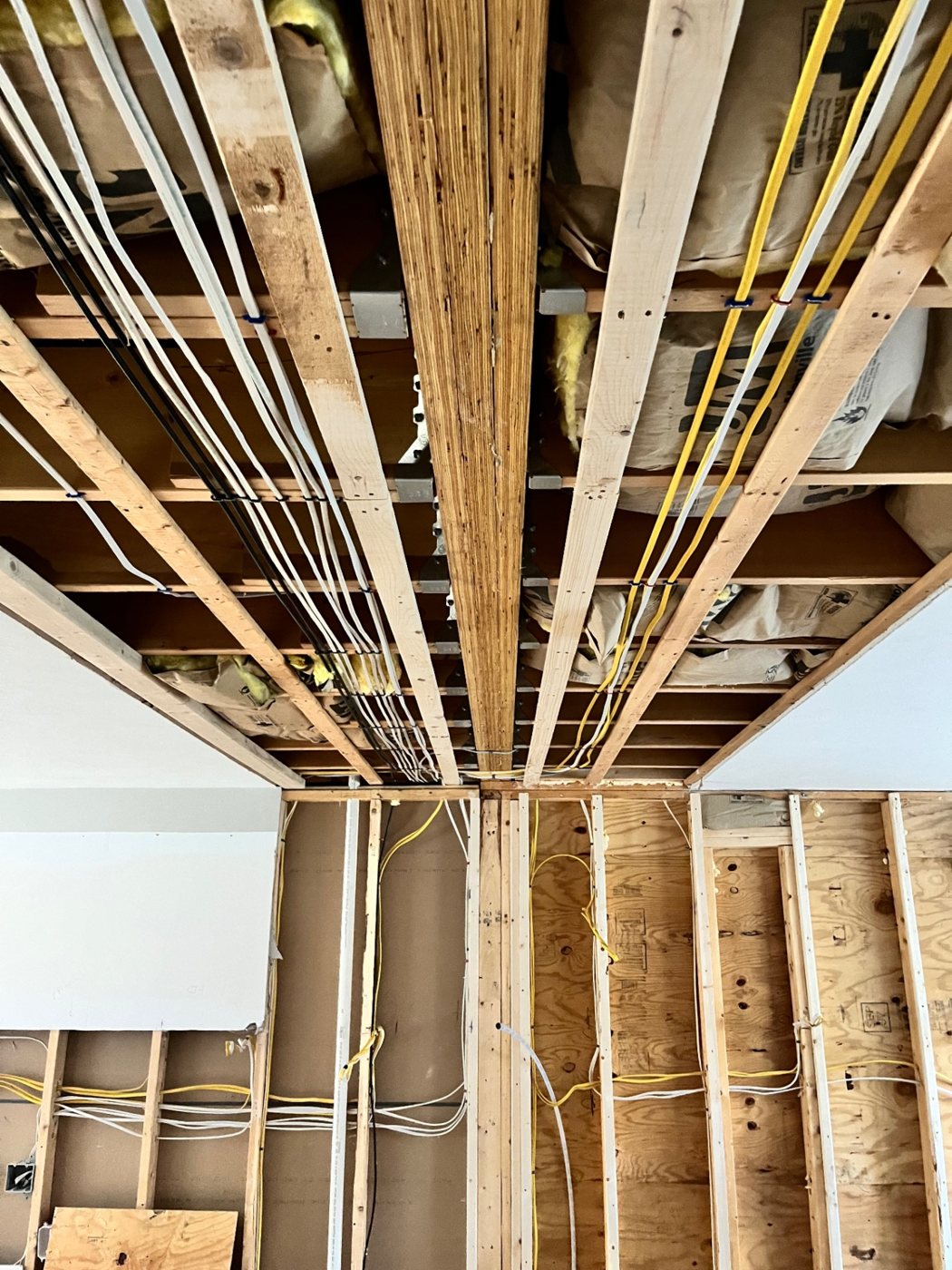 Open ceiling joists with neatly run cable during a renovation rough-in